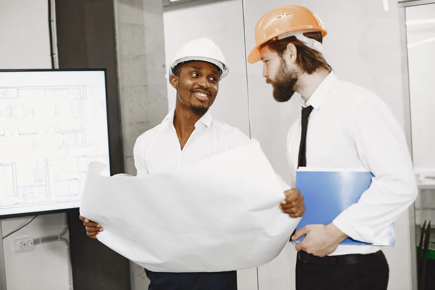 Two contractors in hard hats reviewing building plans